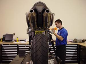 Guy giving service to a motorcycle.